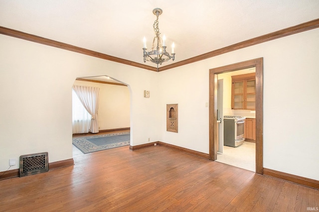 empty room with a notable chandelier, light hardwood / wood-style floors, and crown molding