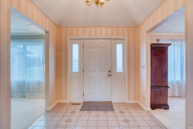 tiled entrance foyer with a textured ceiling and ornamental molding