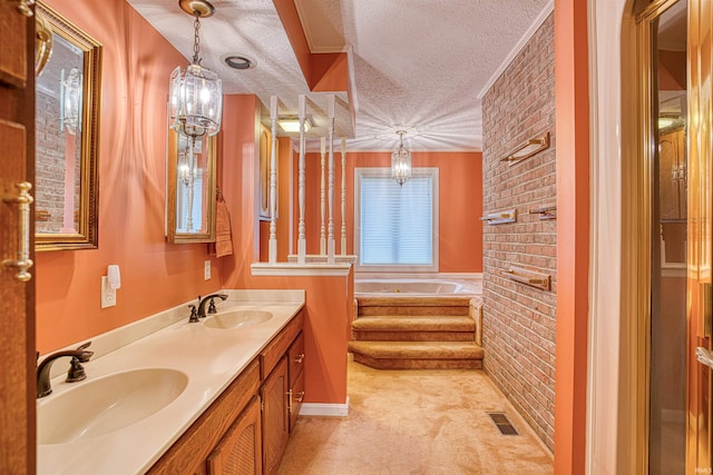 bathroom featuring a washtub, vanity, brick wall, and a textured ceiling