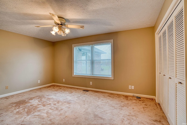 unfurnished bedroom with ceiling fan, a closet, light carpet, and a textured ceiling