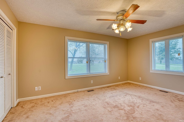 unfurnished bedroom with multiple windows, light carpet, and ceiling fan