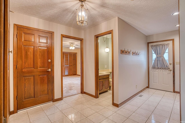 entryway with ceiling fan with notable chandelier, light tile patterned floors, and a textured ceiling