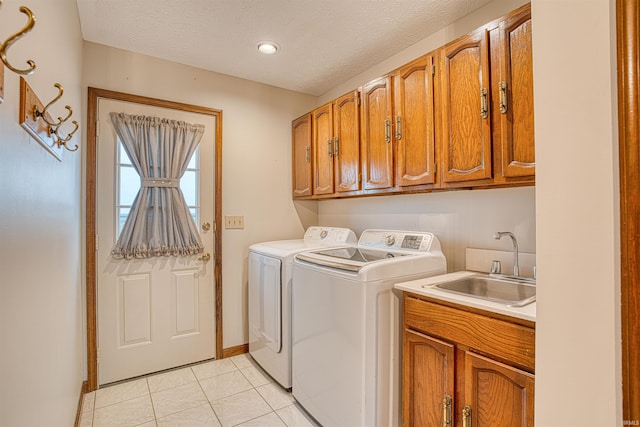 washroom featuring sink, cabinets, separate washer and dryer, a textured ceiling, and light tile patterned flooring