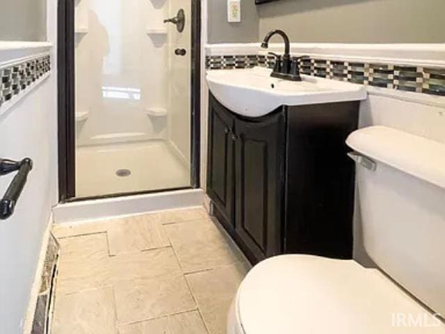 bathroom featuring vanity, toilet, and a shower with shower door