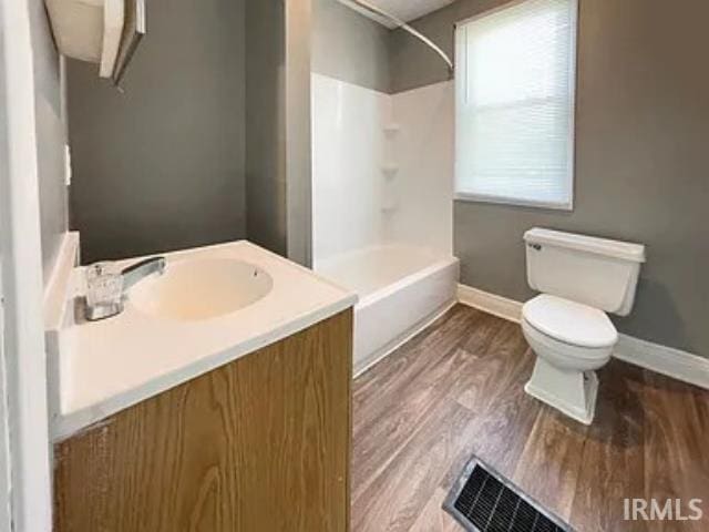 bathroom featuring a shower, vanity, hardwood / wood-style flooring, and toilet