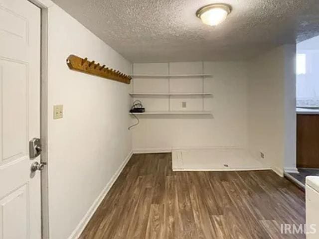 laundry room featuring a textured ceiling and dark hardwood / wood-style flooring