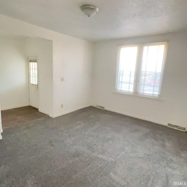 spare room featuring dark colored carpet