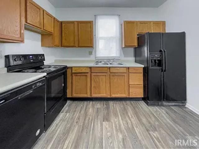 kitchen with black appliances, light hardwood / wood-style floors, and sink