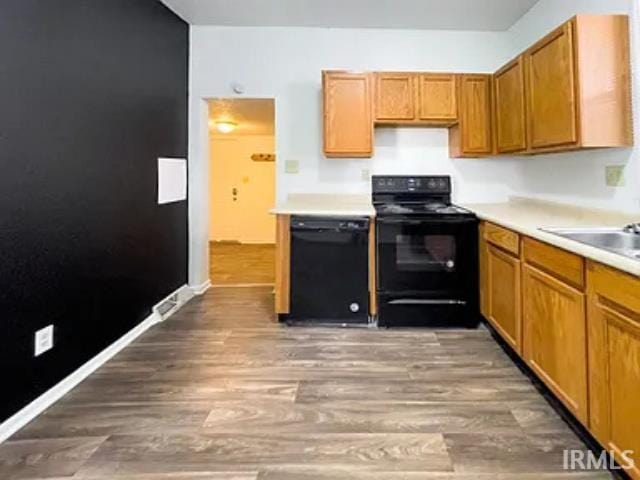 kitchen with black appliances, dark hardwood / wood-style floors, and sink