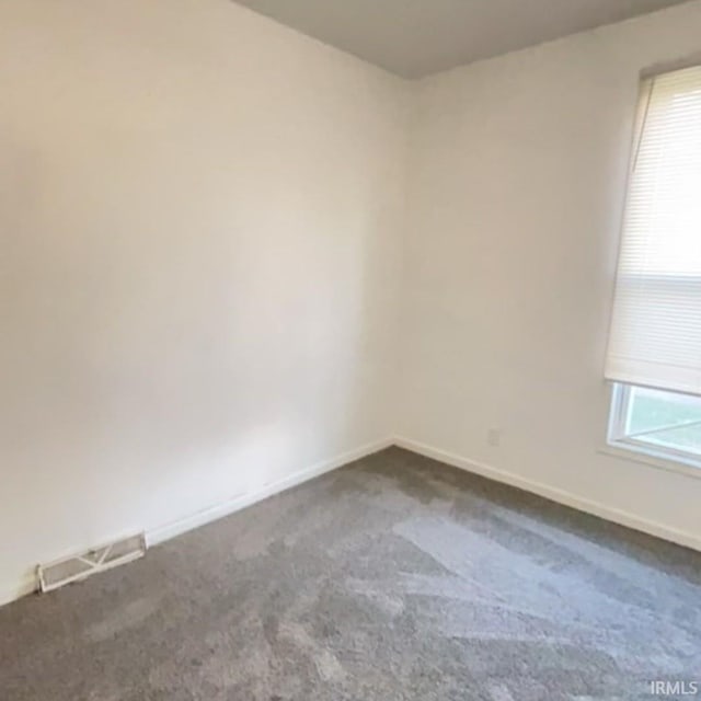 spare room with dark carpet