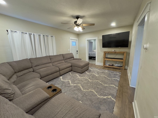 living room featuring ceiling fan and dark hardwood / wood-style flooring