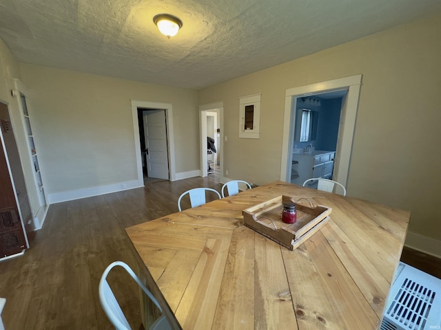 dining area with sink, dark wood-type flooring, and a textured ceiling