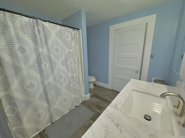 bathroom featuring hardwood / wood-style floors, vanity, toilet, and curtained shower