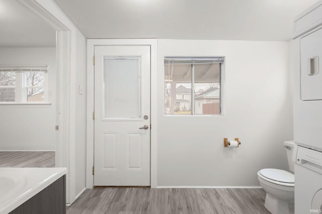 bathroom with stacked washer / dryer, hardwood / wood-style floors, vanity, and toilet