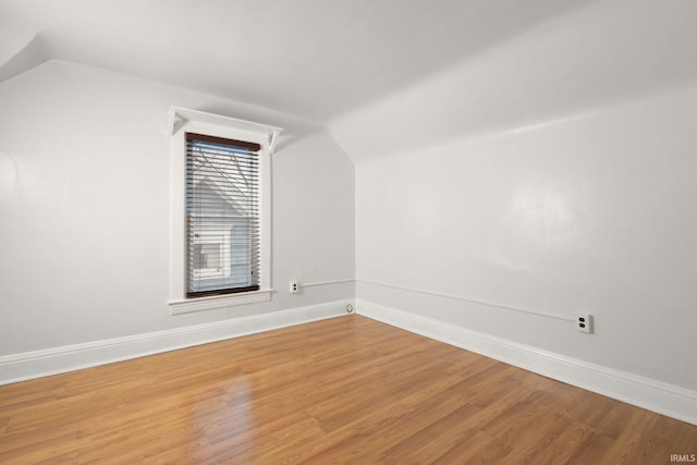 empty room with hardwood / wood-style floors and vaulted ceiling