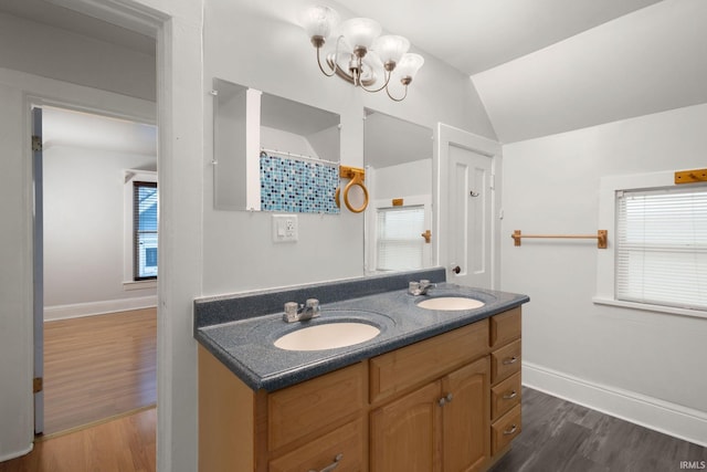 bathroom with a wealth of natural light, vanity, vaulted ceiling, and hardwood / wood-style flooring