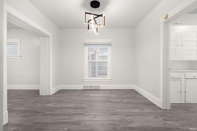 unfurnished dining area featuring a chandelier and dark wood-type flooring