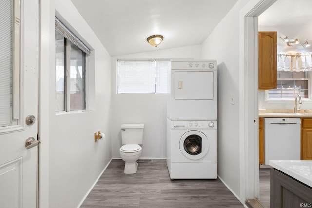 clothes washing area with hardwood / wood-style floors and stacked washer / dryer