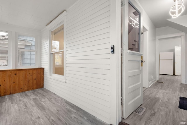 hall featuring light wood-type flooring and wooden walls