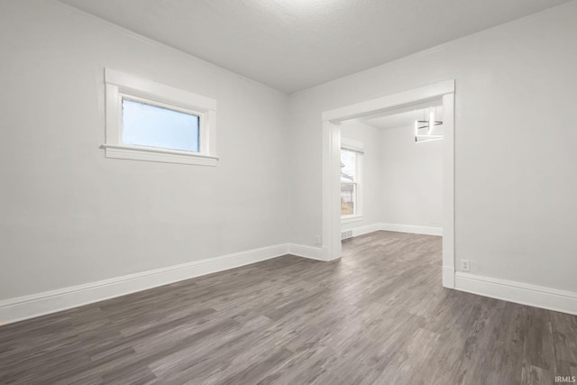 unfurnished room with a textured ceiling, a healthy amount of sunlight, and dark hardwood / wood-style floors