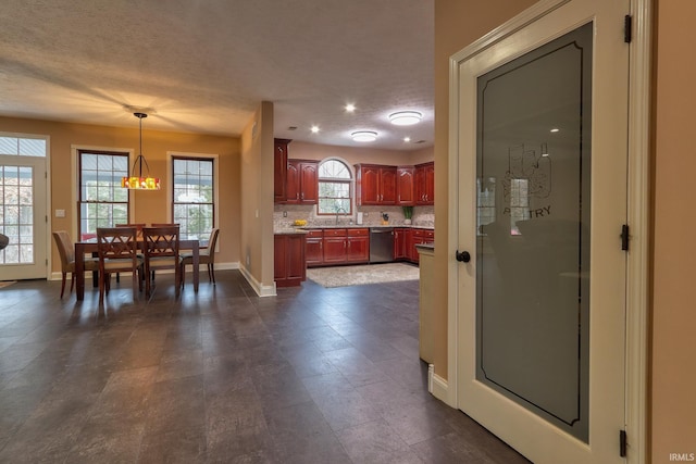 kitchen featuring tasteful backsplash, a wealth of natural light, hanging light fixtures, and stainless steel dishwasher