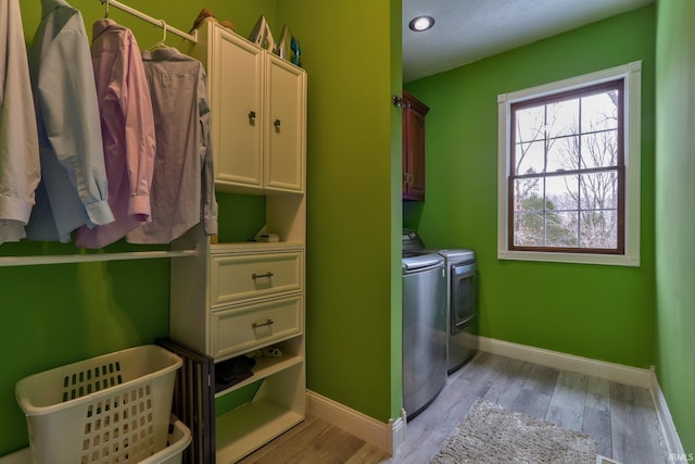 clothes washing area featuring independent washer and dryer, cabinets, and light wood-type flooring