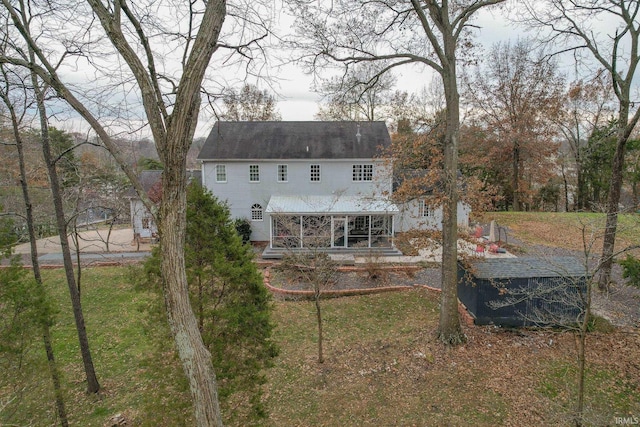 rear view of property featuring a sunroom and a yard