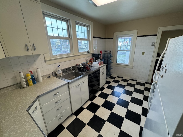 kitchen featuring sink, white cabinetry, black dishwasher, and tile walls