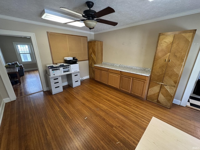 office featuring a textured ceiling, ceiling fan, ornamental molding, and dark wood-type flooring