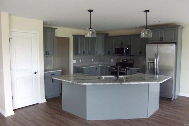 kitchen featuring a kitchen island with sink, dark hardwood / wood-style flooring, decorative light fixtures, and appliances with stainless steel finishes