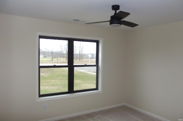 carpeted spare room with a wealth of natural light and ceiling fan