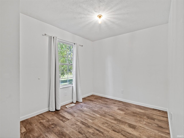 spare room featuring a textured ceiling and hardwood / wood-style flooring