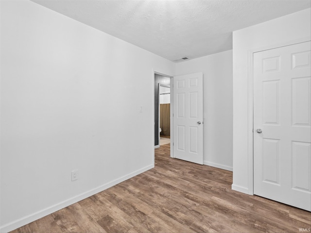 unfurnished bedroom featuring hardwood / wood-style floors and a textured ceiling