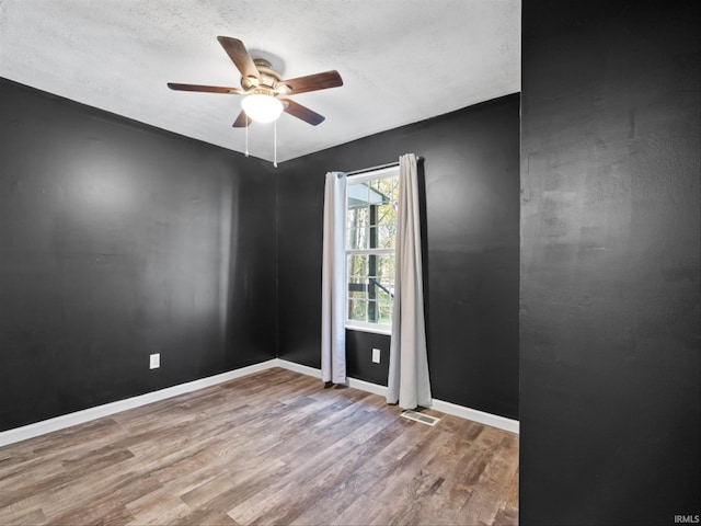 unfurnished room featuring ceiling fan, wood-type flooring, and a textured ceiling