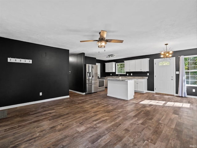 kitchen with appliances with stainless steel finishes, a kitchen island, dark wood-type flooring, decorative light fixtures, and white cabinetry