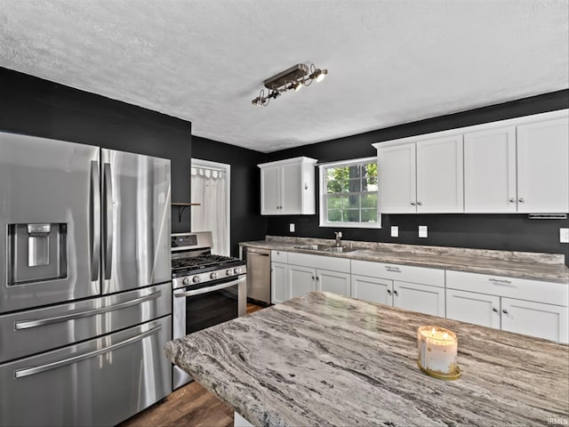 kitchen with white cabinetry, sink, light stone counters, and appliances with stainless steel finishes