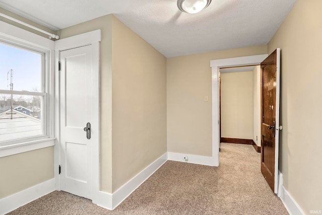 hall featuring light carpet and a textured ceiling