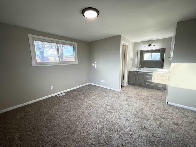 unfurnished bedroom featuring multiple windows, light carpet, and sink