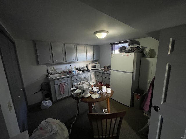 kitchen featuring gray cabinetry, white appliances, and carpet