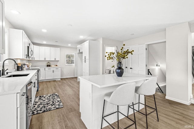 kitchen featuring light hardwood / wood-style floors, white cabinetry, a kitchen island, and sink