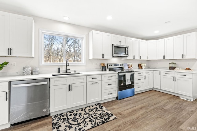 kitchen featuring white cabinetry, sink, appliances with stainless steel finishes, and light hardwood / wood-style flooring