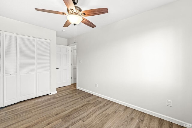 unfurnished bedroom featuring hardwood / wood-style flooring, ceiling fan, and a closet