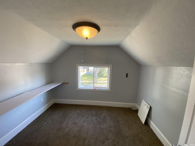 bonus room with vaulted ceiling, a textured ceiling, and dark colored carpet