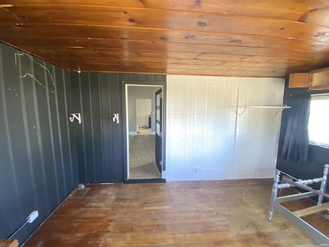 spare room with dark hardwood / wood-style flooring, wooden ceiling, and wooden walls