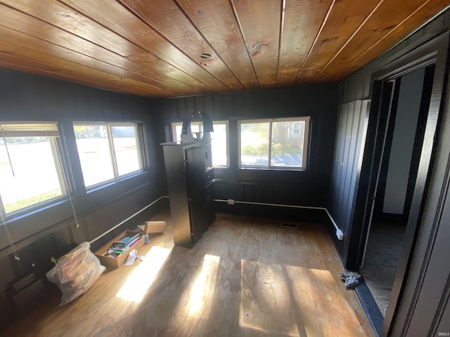 empty room with hardwood / wood-style floors, plenty of natural light, and wood ceiling