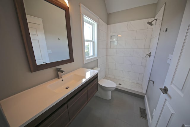 bathroom with tiled shower, vanity, and toilet