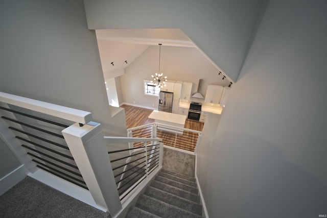 staircase with carpet floors, high vaulted ceiling, and a chandelier