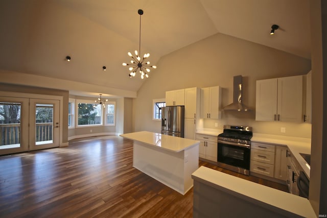 kitchen featuring high vaulted ceiling, an inviting chandelier, white cabinets, wall chimney range hood, and stainless steel appliances