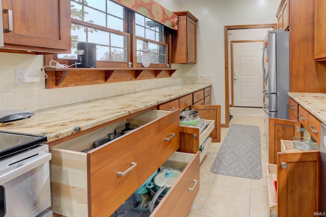 kitchen featuring stainless steel fridge, light tile patterned flooring, and light stone counters