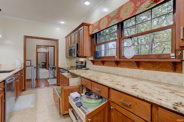 kitchen featuring appliances with stainless steel finishes, tasteful backsplash, light stone counters, ornamental molding, and light tile patterned flooring